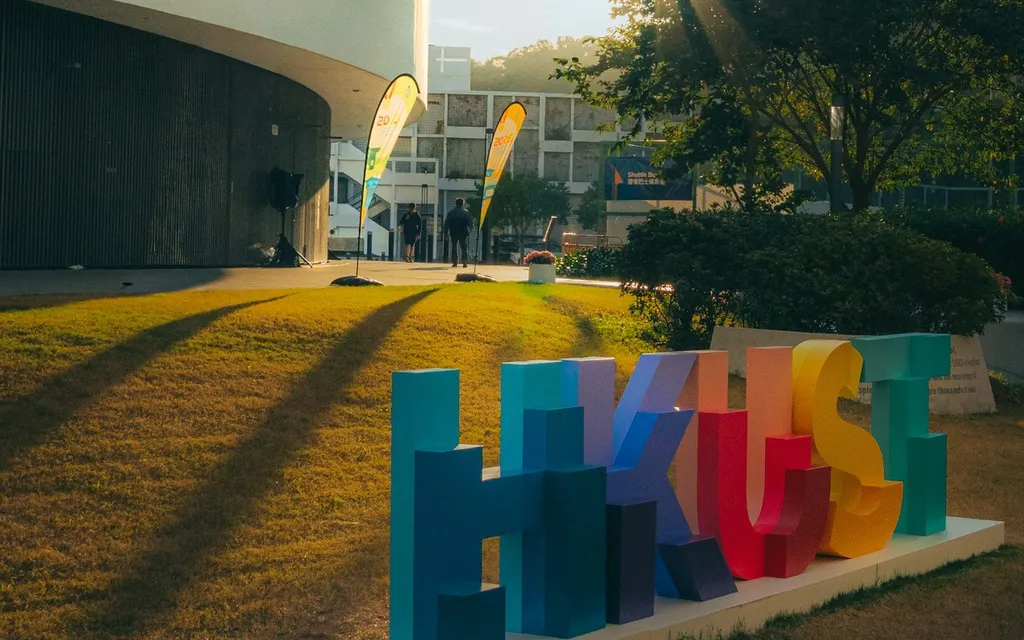 港科大草坪上的彩色 HKUST 字样标识，夕阳光线。